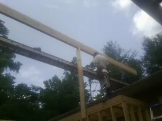 Carpenter setting a ridge beam over a new addition frame — Ice Dam Removal by Roofing Brothers in Morris Chapel