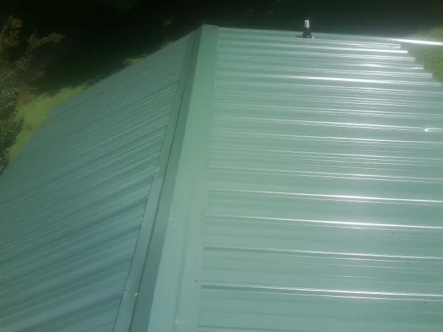 New green metal panels meeting at the ridge of a roof — Flat Roof Repair work by our crew in Morris Chapel