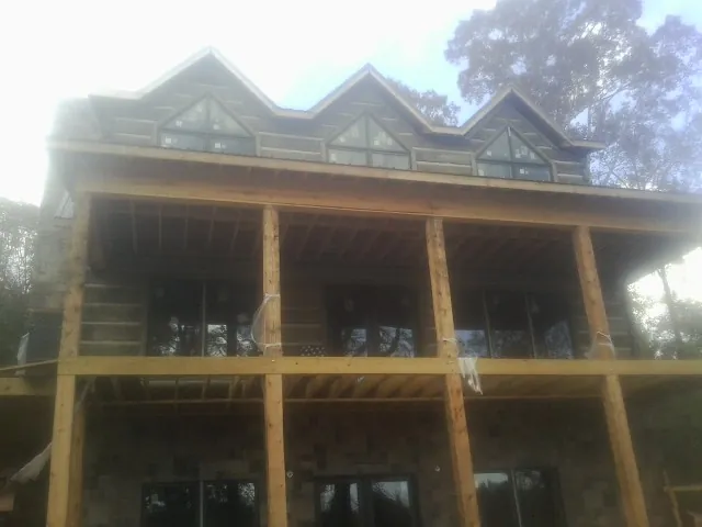 Dormers and porch framing on a large log home under construction — Roof Coating work by our crew in Morris Chapel