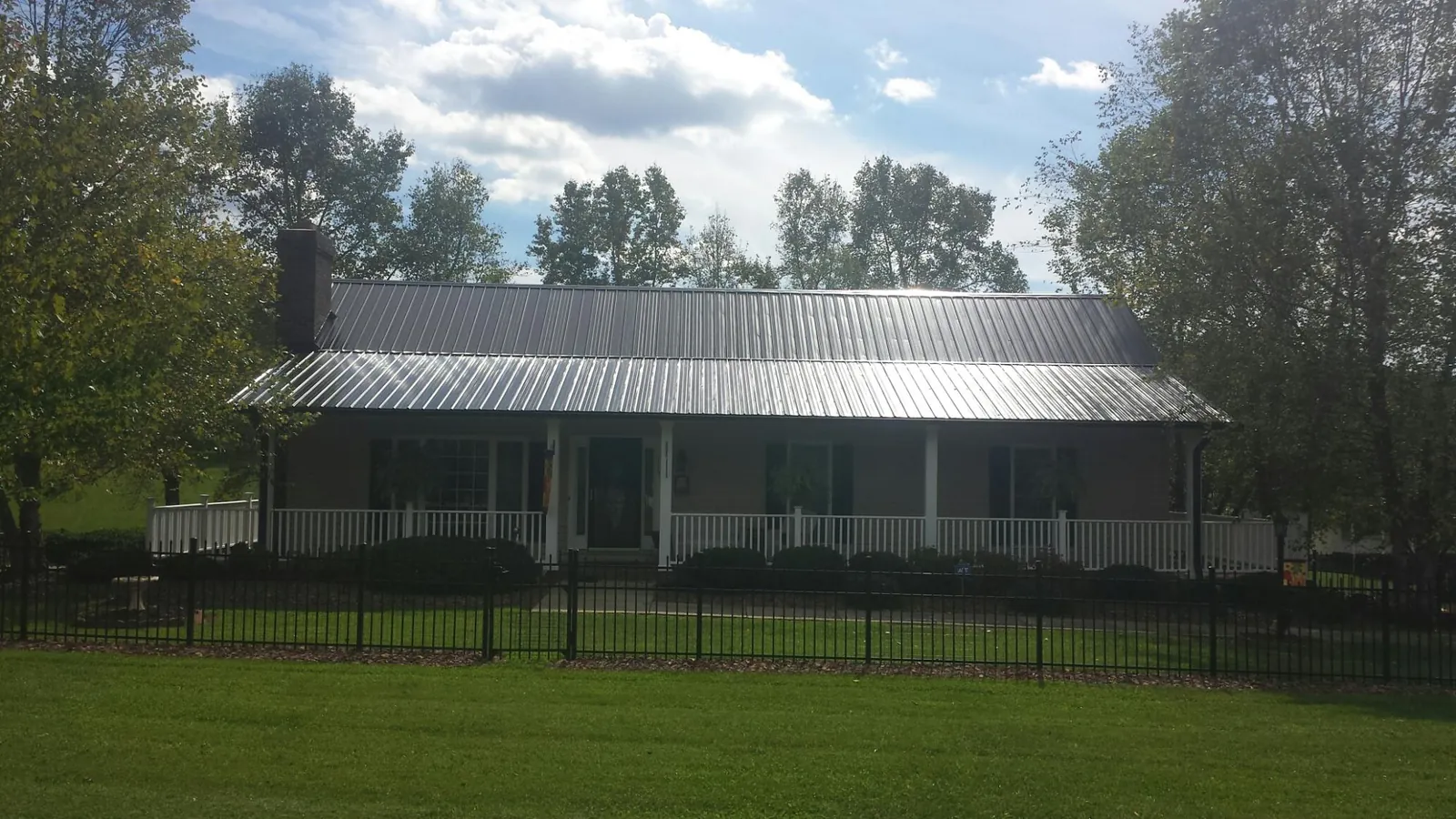 Gray metal roof on a brick ranch with a full width front porch — Gutter Guard Installation work by our crew in Morris Chapel