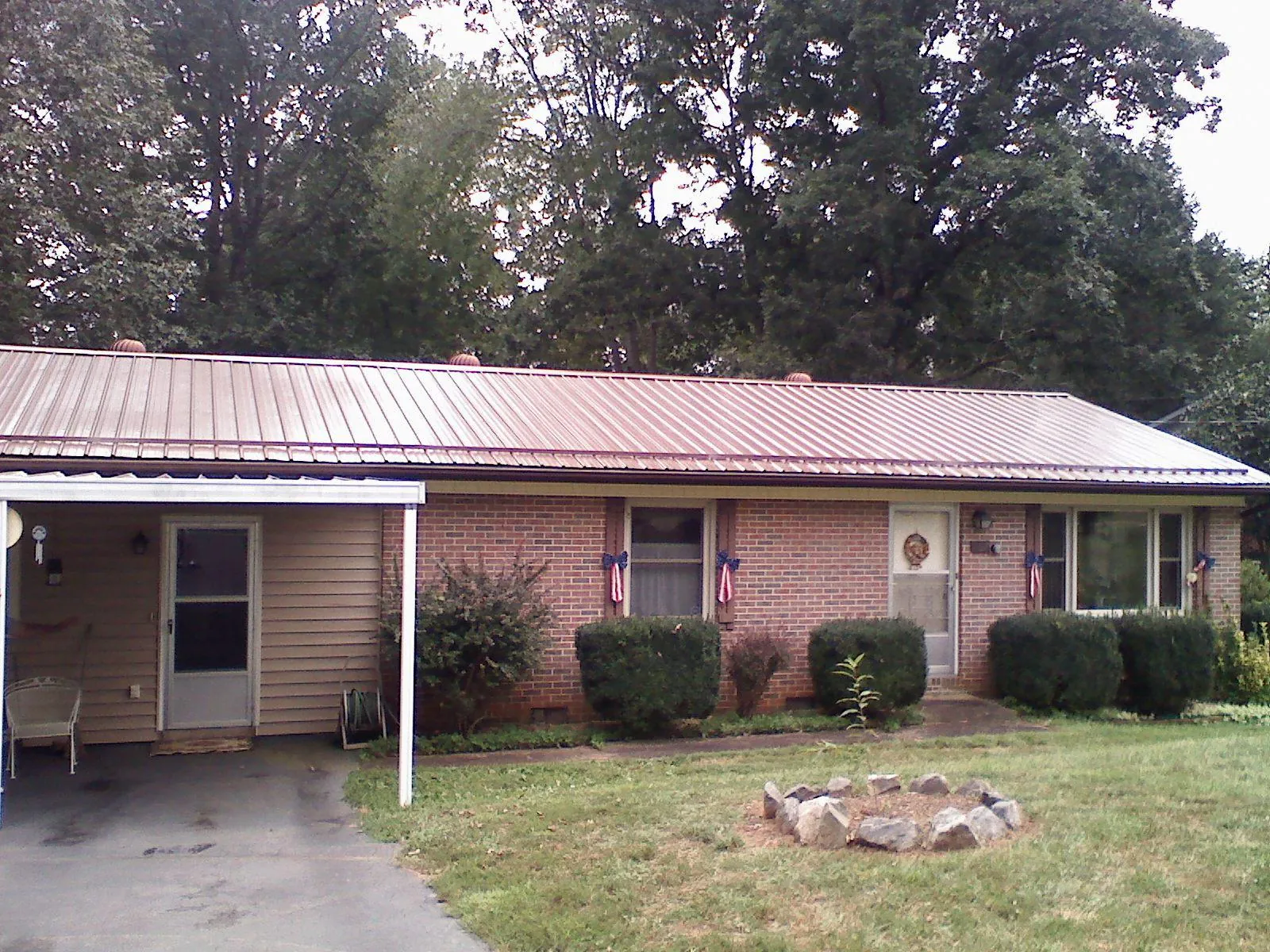 Bronze metal roof and carport on a brick ranch home — Roof Repair work by our crew in Morris Chapel