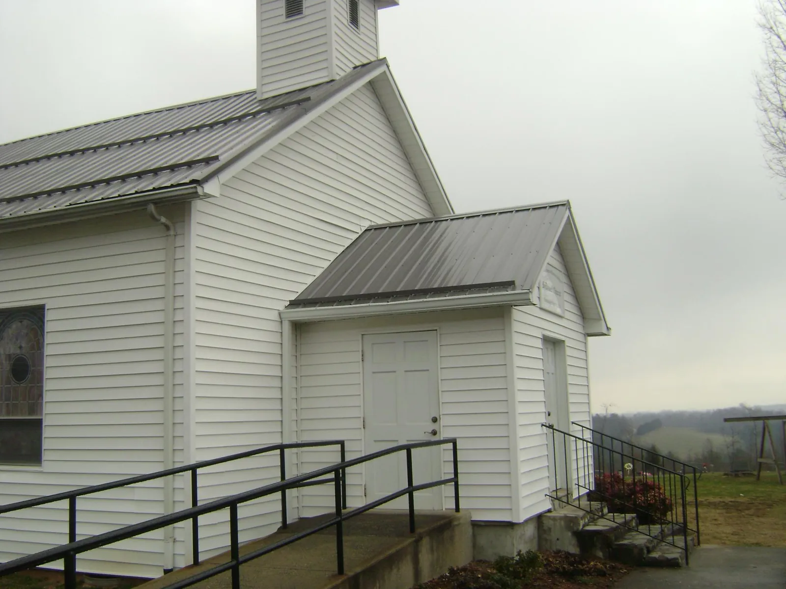 Gray metal roof on a white clapboard church with a steeple in Morris Chapel