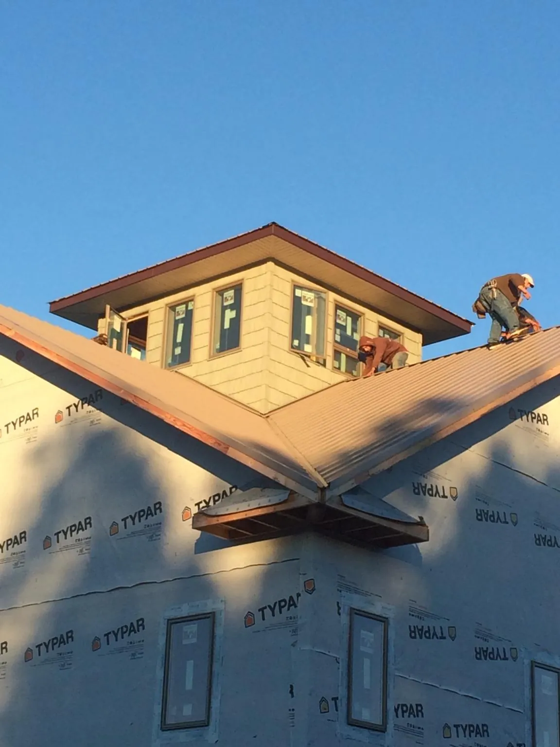 Roofers working around a rooftop cupola on a new metal roof at sunset — Roof Waterproofing in Morris Chapel by Roofing Brothers